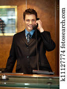 Cheerful front desk executive attending phone call