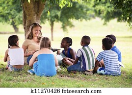 Children and education, teacher reading book to young students Children and education, teacher reading book to young students