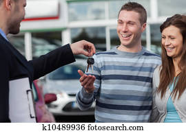 Couple receiving car keys by a dealer