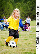 Cute young girl in uniform playing in organized youth league soccer game