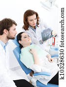 Dentist and his assistant explain details of the x ray image to the patient