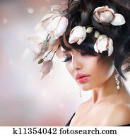 Fashion Brunette Girl with Magnolia Flowers. Hairstyle