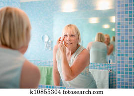 Female beauty, old woman applying cream on face at home Female beauty, old woman applying cream on face at home