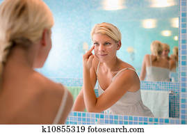 Female beauty, young woman applying lotion on face at home Female beauty, young woman applying lotion on face at home