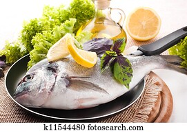Fresh fish of dorado on a frying pan with a lemon and olive oil