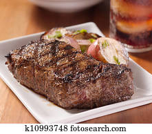 grilled steak with potatoes and cola in background. grilled steak with potatoes and cola in background.