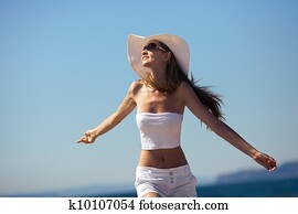 Happiness bliss freedom concept. Woman happy smiling joyful with arms up dancing on beach in summer during holidays travel. 
