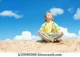 Happy child sitting in lotus position over bllue sky on the top. Happiness and freedom concept.