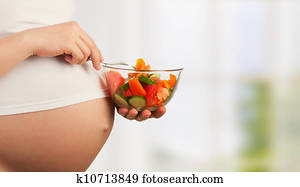 healthy nutrition and pregnancy. pregnant woman's belly and vegetable salad healthy nutrition and pregnancy. pregnant woman's belly and vegetable salad