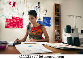 hispanic woman doing budget in fashion designer atelier