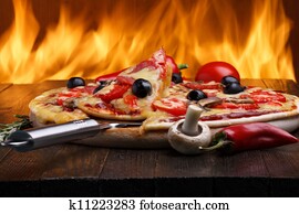 Hot pizza with oven fire on background