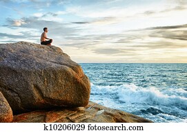 Man practices yoga on coast - meditation Man practices yoga on coast - meditation