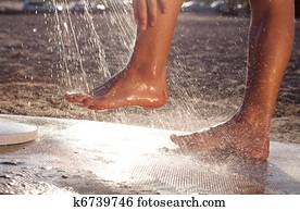 man washing his feet at the beach