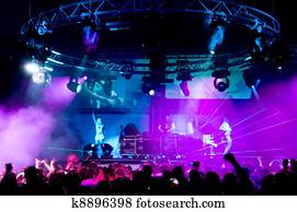 People relaxing at the concert, anonymous girls on the stage