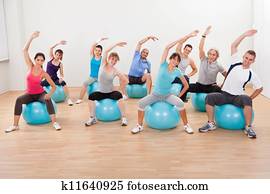 Pilates class exercising in a gym Pilates class exercising in a gym