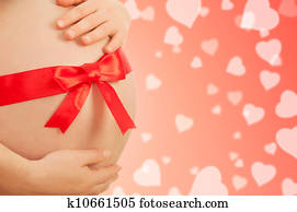 pregnant belly  of woman with red ribbon
