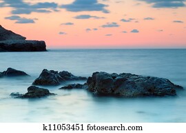 Seashore with misty water at sunset