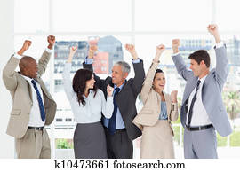 Smiling business people looking at each other and raising their arms in success