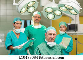 Smiling surgeon sitting with a team behind him