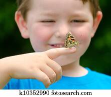 Spring concept with close up of a painted lady butterfly, Vanessa cardui, being held by child playing outdoors in nature Spring concept with close up of a painted lady butterfly, Vanessa cardui, being held by child playing outdoors in nature