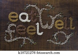 The phrase 'Eat Well, Be Well', written and decorated in seeds