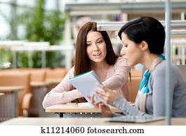 Two women speak sitting at the table