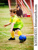 Young child boy playing soccer during organized league game