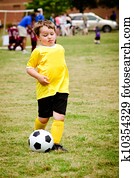 Young child boy playing soccer during organized league game