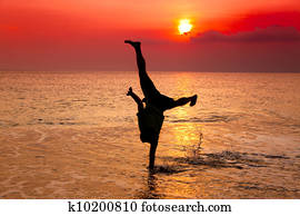 young clovek, hand stand, on  morske pobrezie, na, západ slnka