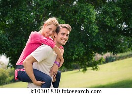 young couple running piggyback in city park young couple running piggyback in city park