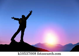 young man standing on the top of mountain and  watching the sunrise
