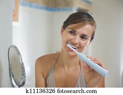 Young woman brushing teeth with electric toothbrush