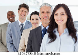 צעיר, לחייך, איש עסקים עומד, ב, a, well-lit, חדר, בין, שלו, חברי לעבודה