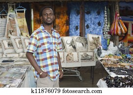african curio salesman vendor in front of wildlife items african curio salesman vendor in front of wildlife items