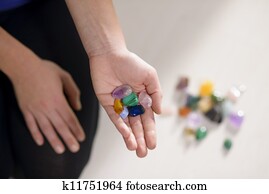 Alternative medicine, pain healing and women, young therapist choosing crystals for reiki therapy and showing them to camera