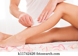 Beautician waxing a woman leg Beautician waxing a woman leg