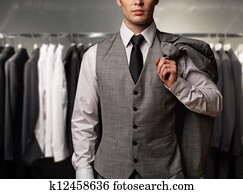 Businessman in classic vest against row of suits in shop