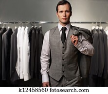 Businessman in classic vest against row of suits in shop