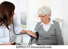 Closeup of nurse checking senior woman blood pressure