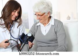 Closeup of nurse checking senior woman blood pressure