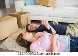 Couple lying on the floor with their moving boxes