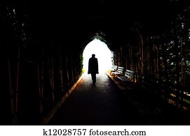 Lonely man is walking through dark tunnel to the light
