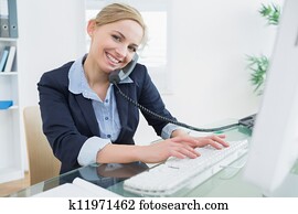 Portrait of business woman using phone and computer at desk Portrait of business woman using phone and computer at desk