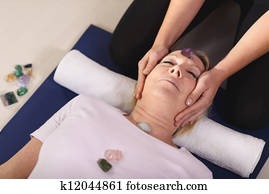 Reiki therapy with girl working as spirit healer, arranging crystals and gemstones on female client for treatment Reiki therapy with girl working as spirit healer, arranging crystals and gemstones on female client for treatment