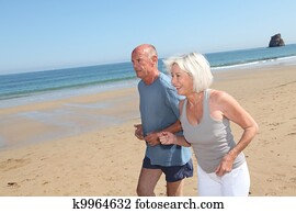 Senior couple jogging on a sandy beach