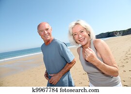 Senior couple jogging on a sandy beach
