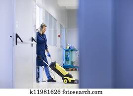 Woman working, professional maid cleaning and washing floor with machinery in industrial building. Full length, copy space Woman working, professional maid cleaning and washing floor with machinery in industrial building. Full length, copy space