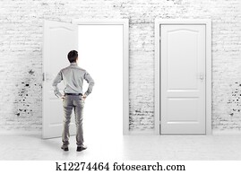 young business man in front of an open door in a vintage white brick wall young business man in front of an open door in a vintage white brick wall