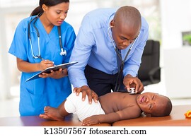 african pediatrician with nurse assistant examining a child african pediatrician with nurse assistant examining a child
