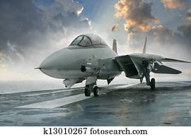 An F-14 Tomcat jet fighter sits on the deck of an aircraft carrier deck beneath dramatic clouds An F-14 Tomcat jet fighter sits on the deck of an aircraft carrier deck beneath dramatic clouds